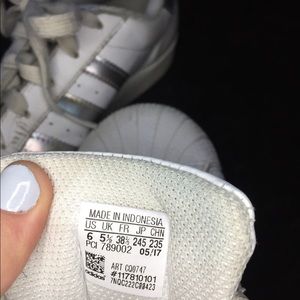 White Adidas super stars with holographic stripes.